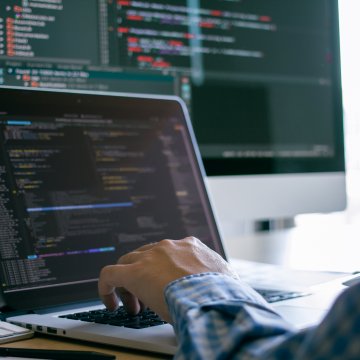 Person at a computer screen with code on the monitor